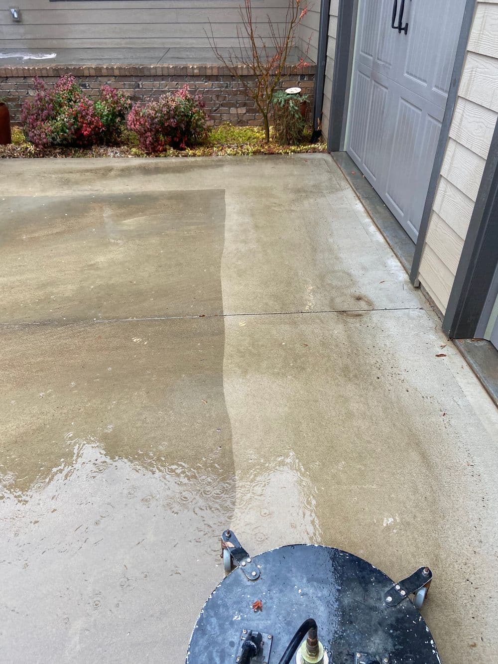 Pressure washing before and after on a concrete driveway with clean and dirty sections.