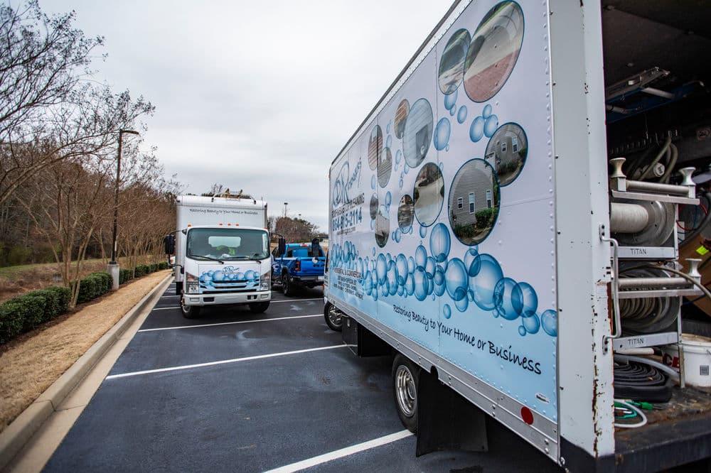 Cleaning service truck with bubble-themed design parked in a commercial lot.
