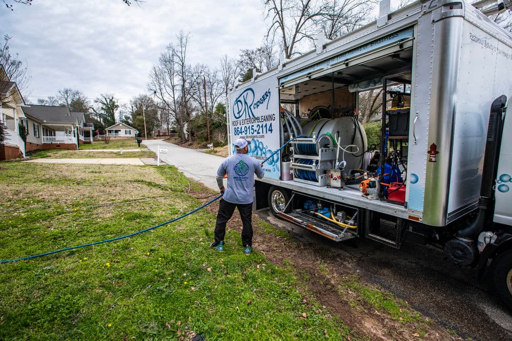 Technician operating a pressure cleaning truck in a residential area.