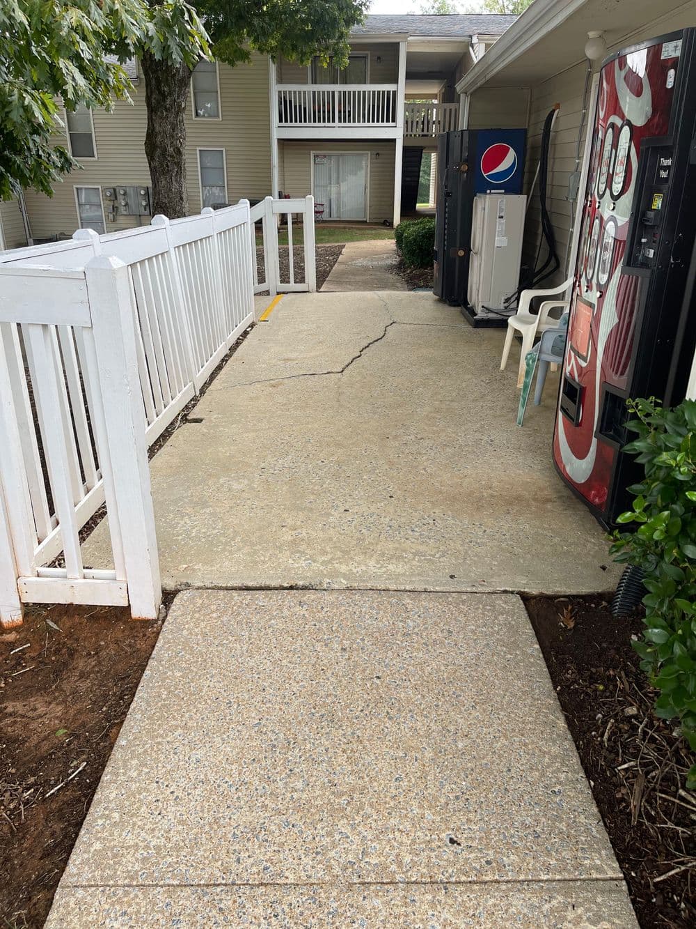 Cracked concrete walkway leading to vending machines at an apartment complex.