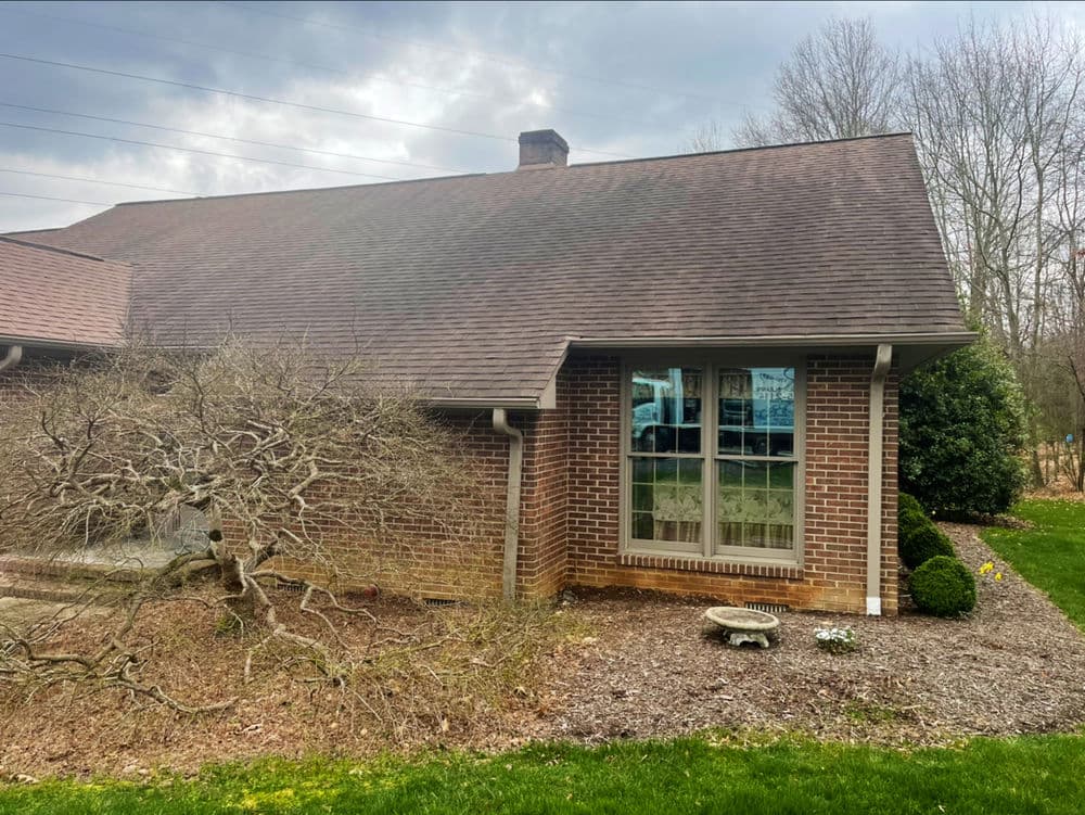 Brick home exterior with a sloped roof, window view, and landscaped garden.